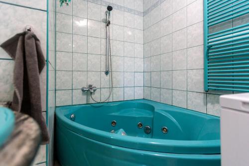 a blue tub in a tiled bathroom with a shower at Zsuzsa Apartmanház in Sukoró