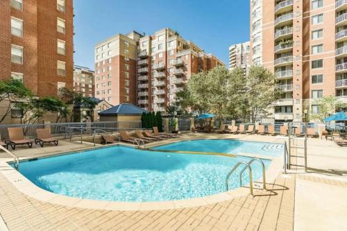 a large swimming pool with chairs and buildings at Elegant and Charming Condo at Ballston with Pool in Arlington
