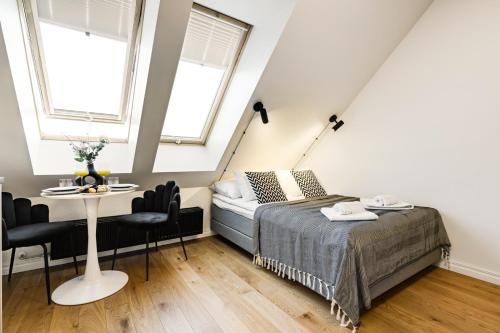 a bedroom with a bed and a table and two windows at Tempus Te Avangard Tallinn with terrace and gym in Tallinn