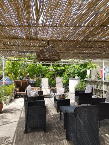 a patio with chairs and tables and a straw roof at Petalo Rosso b&b in Lenola