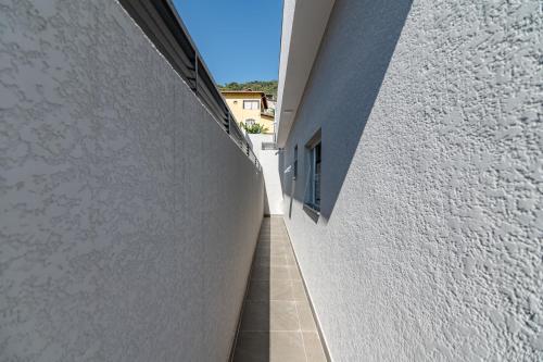 a hallway of a white building with a tile floor at Pousada Casa da Cidinha in Extrema