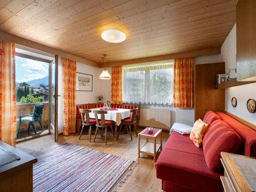 a living room with a red couch and a table at Ferienwohnungen Haus Schwaiger in Fieberbrunn