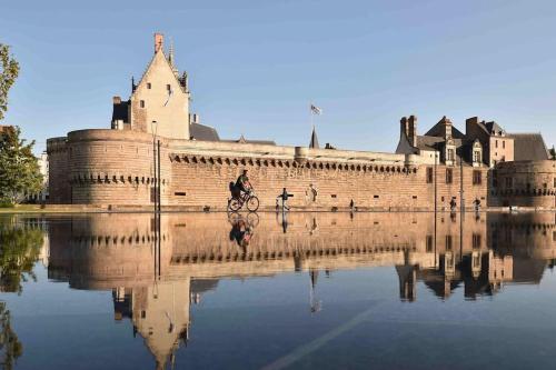 a castle with its reflection in the water at La villa du pressoir, classé 3 étoiles meublé de tourisme in Le Pallet