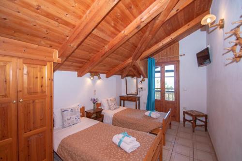 two beds in a room with wooden ceilings at Arpyia in Vasilikos
