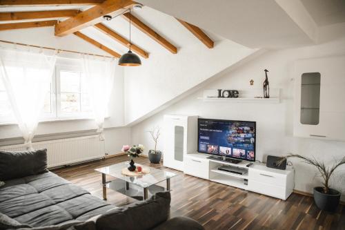 uma sala de estar com um sofá e uma televisão em Modernes Apartment mit Top Ausstattung und Kamin im Oberpfälzer Seenland em Nittenau