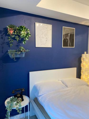 1 dormitorio con pared azul, cama y mesa en Marshall’s Place Azure Staycation, en Manila