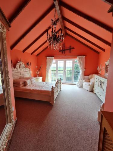 埃爾默頓的住宿－Barley View，一间卧室设有橙色的墙壁和一张带吊灯的床。