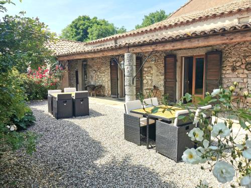 ein Steinhaus mit einem Tisch und Stühlen im Hof in der Unterkunft Le Barry du Grand Chemin in Le Caylar