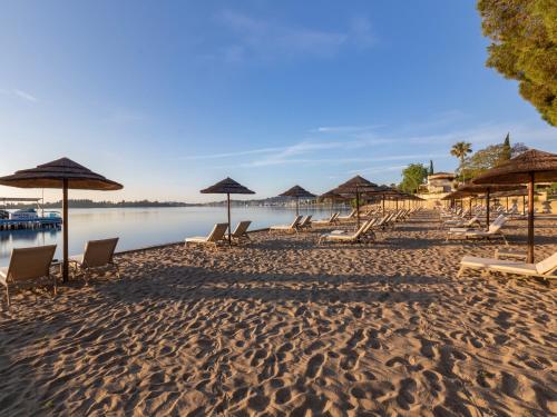 a sandy beach with chairs and umbrellas on it at Dreams Corfu Resort & Spa - All Inclusive in Gouvia