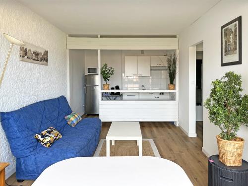 un salon avec un canapé bleu et une cuisine dans l'établissement En bord de mer, Seignosse Penon, à Seignosse