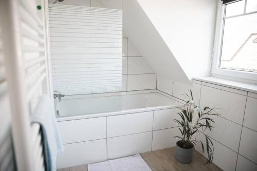 uma casa de banho branca com uma banheira e um vaso de plantas em Modernes Apartment Schwarzenfeld em Schwarzenfeld