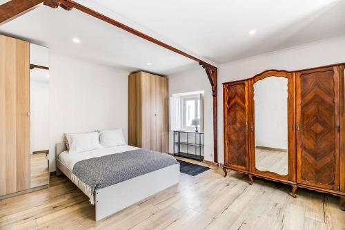 een slaapkamer met een bed en een houten kast bij Ap. Vila Oeiras 5m a pé da praia in Oeiras