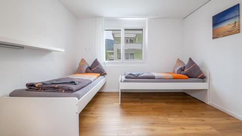 two beds in a room with white walls and a window at Anstatthotel Goldau - self-check-in in Goldau