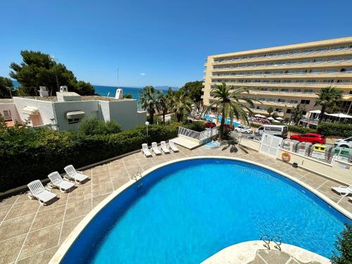 a large swimming pool with chairs and a building at Domuum Holidays - FONT DE MAR in Salou
