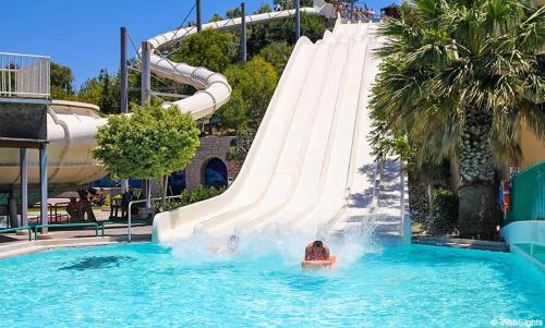 a group of people in a water slide in a pool at VOULA APARTMENTS in Faliraki