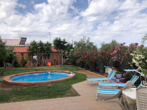 a backyard with a pool and chairs and flowers at Hospitality in Mythical and Historical Peloponnese1 in Posidhonía