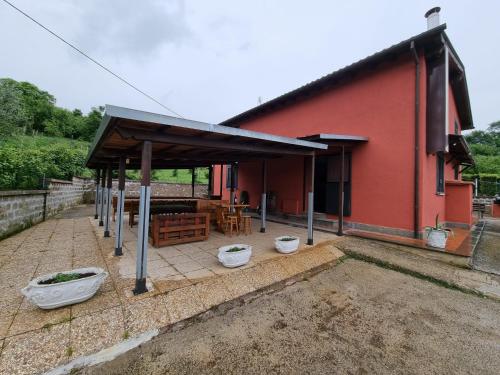 a red building with a pavilion with tables and chairs at Country house Dolce Nocciola in Vignanello