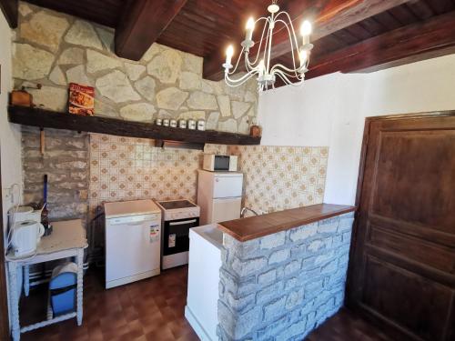 a kitchen with a stone wall and a chandelier at Gîte Le Barry in Le Caylar