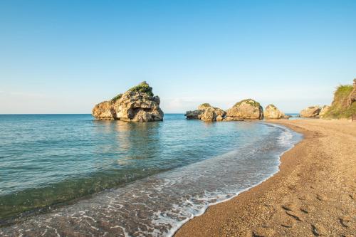 a beach with rocks in the ocean at Arpyia in Vasilikos