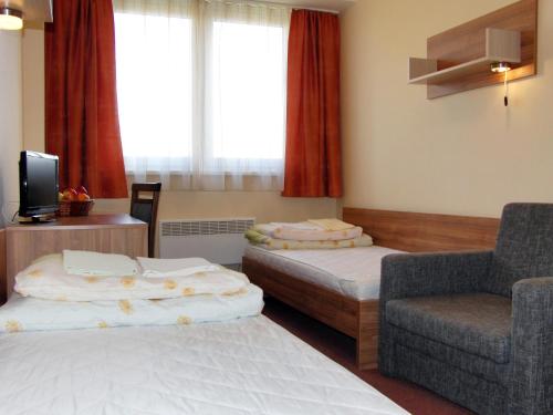 a hotel room with two beds and a chair at Rekreačné zariadenie Crocus in Vysoké Tatry