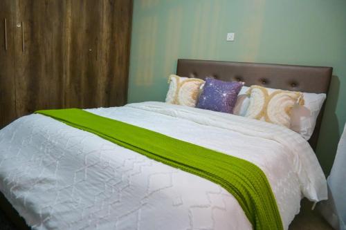 a bed with a green blanket on top of it at Executive apartments at kileleshwa estate in wote town in Wote