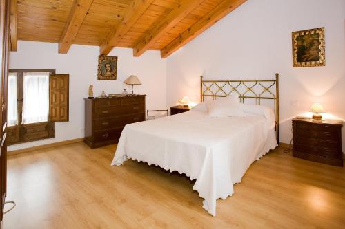 a bedroom with a large white bed and wooden floors at El Molino de la Hiedra in Albeta