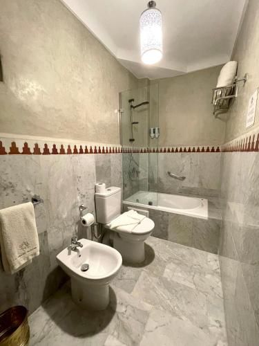 a bathroom with a toilet and a sink and a tub at Le Grand Alcazar - Riad in Fès
