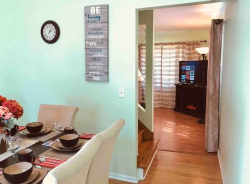 a dining room table with chairs and a clock on the wall at The Ultimate Escape. Unpack, Relax, Enjoy!Sleeps14 in Elmhurst