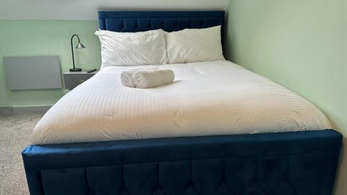 a bed with a blue head board with a towel on it at Homestay in Walsall in Walsall