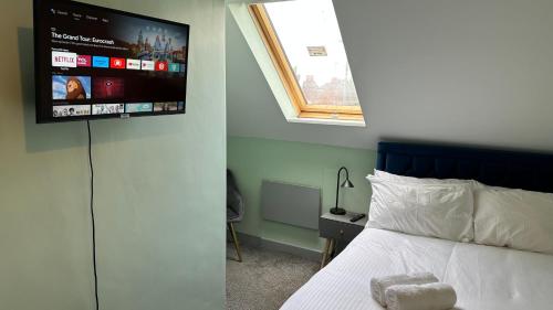 a bedroom with a bed with a tv on the wall at Homestay in Walsall in Walsall