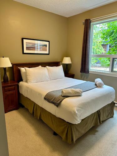 a bedroom with a large bed and a window at Race Rocks Townhouse - Sooke in Sooke