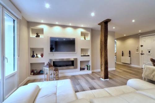 uma sala de estar com um sofá branco e uma televisão em Habitaciones Turísticas Bilbao Centro con aire acondicionado em Bilbau