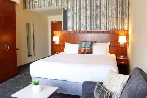 a hotel room with a large bed and a couch at Courtyard Burlington Harbor in Burlington