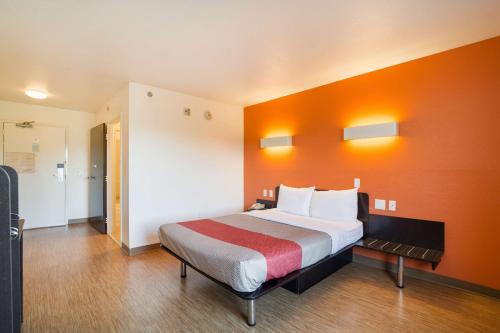Motel 6 - Augusta, GA في أوغوستا: غرفة نوم بسرير كبير بجدار برتقالي