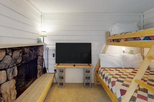 Schlafzimmer mit einem TV, einem Bett und Etagenbetten in der Unterkunft Slope-Walk Condo in Sandpoint