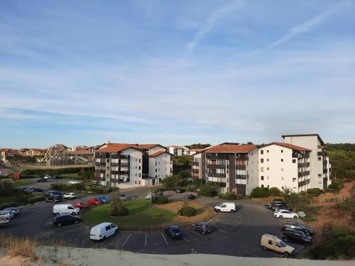 Un estacionamiento con autos estacionados y complejos de apartamentos. en Joli T2 38 m2 rénové idéalement situé, en Seignosse