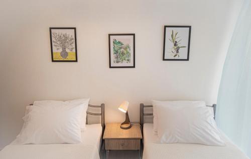 two beds in a room with three pictures on the wall at Viny Apartment in Paralia Dionysiou