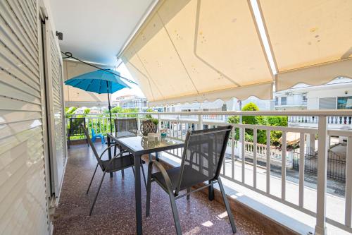 a balcony with a table and chairs and an umbrella at Viny Apartment in Paralia Dionysiou
