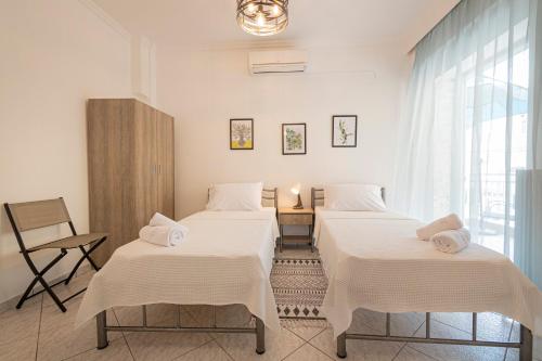 two beds in a room with a window at Viny Apartment in Paralia Dionysiou