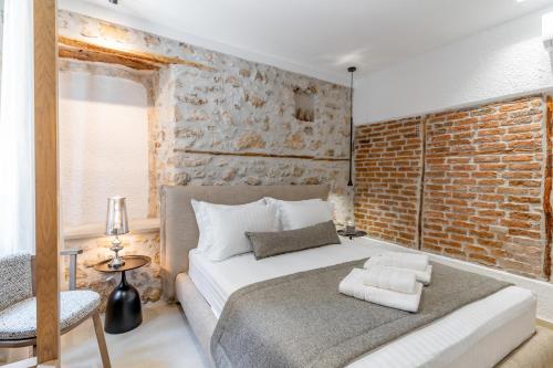 a bedroom with a bed and a brick wall at IKIA KATSANI in Afitos