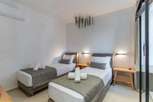 two beds in a room with two tables at IKIA KATSANI in Afitos