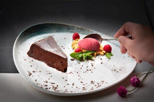 a person eating a piece of chocolate cake on a plate at Garden & SPA Hotel Das Götzfried in Regensburg