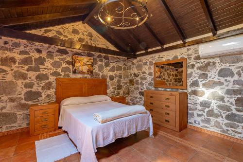 a bedroom with a bed and a stone wall at Casa Los Pinos in Mogán