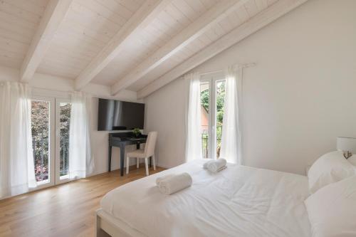 a white bedroom with a bed and a desk at Olmo Suites in Como