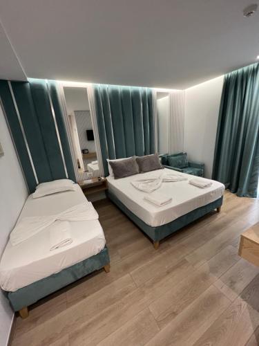 two beds in a room with green curtains at Ilio Boutique Hotel in Ksamil
