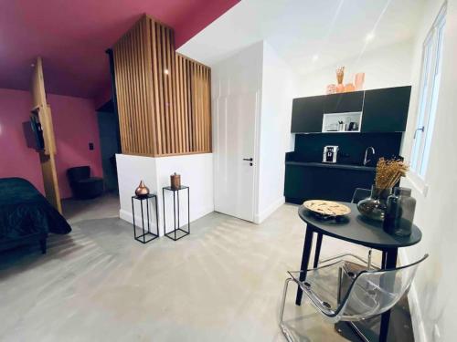La Litchi Le 50 Suites and Spa centre ville في بوردو: غرفة معيشة مع طاولة وجدار أرجواني