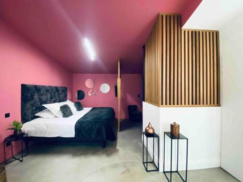 sypialnia z różowymi ścianami i dużym łóżkiem w obiekcie La Litchi Le 50 Suites and Spa centre ville w mieście Bordeaux