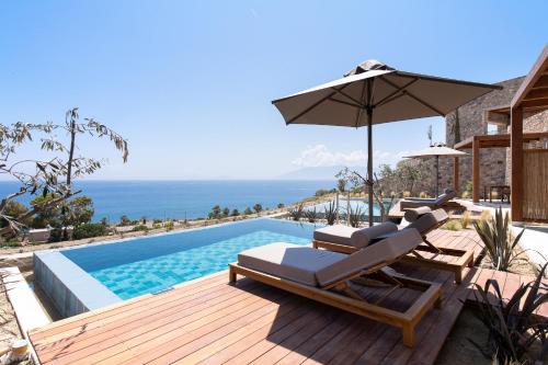 a villa with a swimming pool and an umbrella at KOIA All - Suite Well Being Resort - Adults Only in Agios Fokas