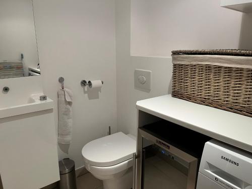 - une salle de bains blanche avec des toilettes et un panier dans l'établissement Appartement moderne face à la mer, à Sanary-sur-Mer