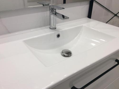 a white bathroom sink with a chrome faucet at Le PANORAMA Maison Blanche in Tulle